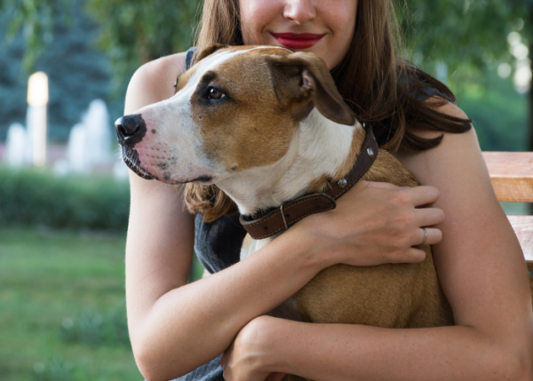 A woman holding her dog in the arms of him.