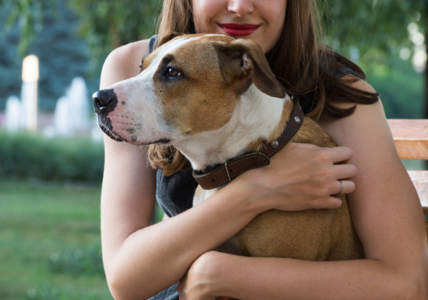 A woman holding her dog in the arms of him.
